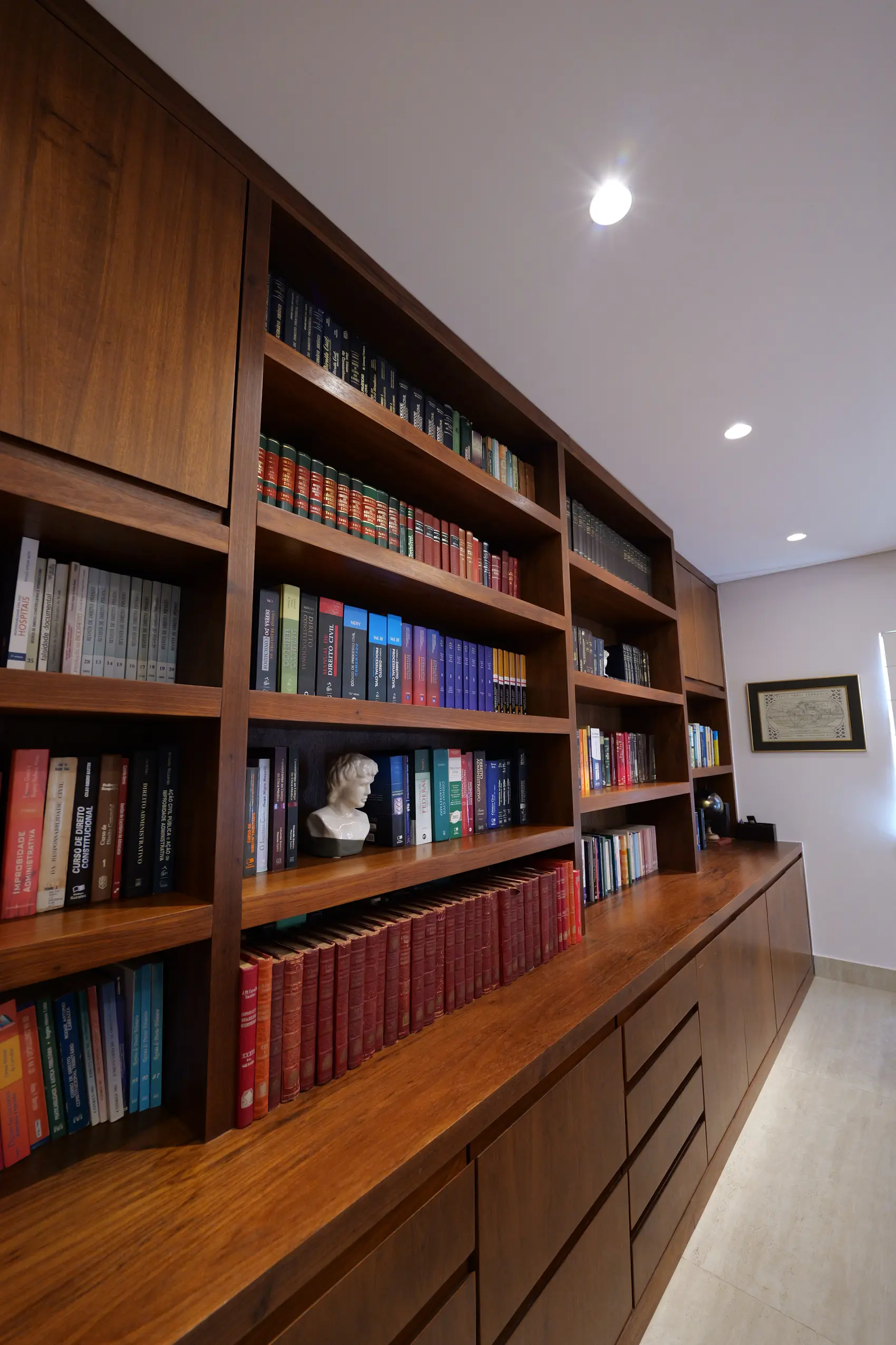 Biblioteca jurídica do escritório, com estantes de madeira do piso ao teto